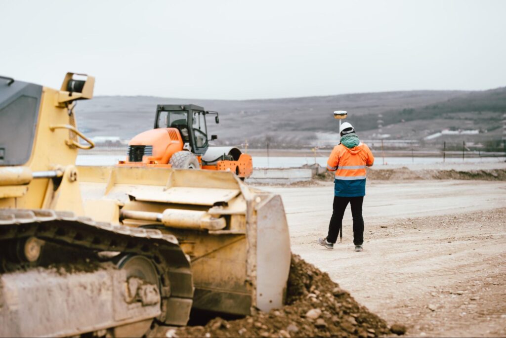 A construction machine and worker preparing for winter projects in Manitoba’s tight seasonal schedules.