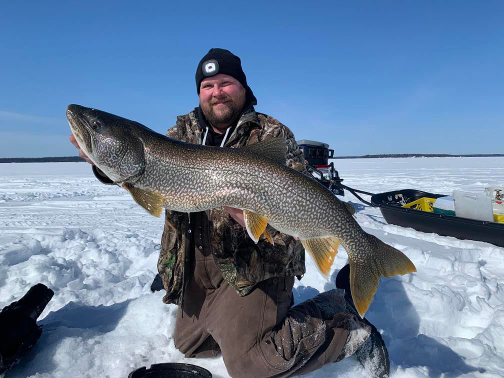 Man smiling while holding a large ice fishing catch