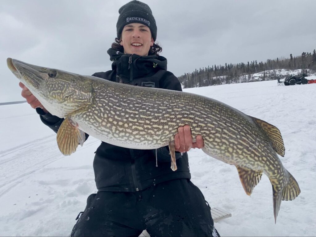 Young man holding a trophy fish during guided ice fishing trip