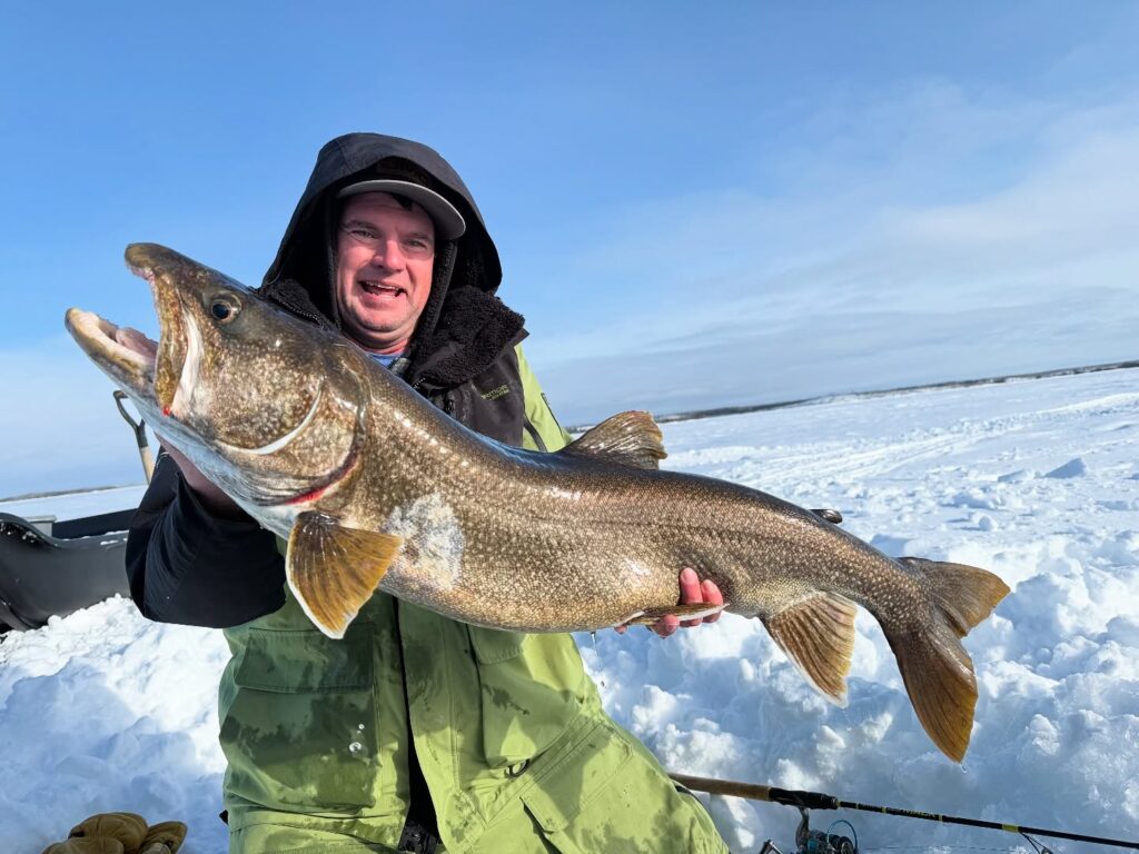 Angler showing a big fish caught while ice fishing on Kamachauwie Lake.