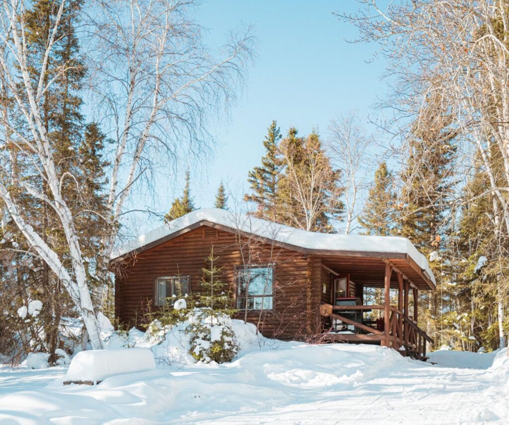Winter exterior view of a cozy cabin at a Manitoba Ice Fishing Lodge.