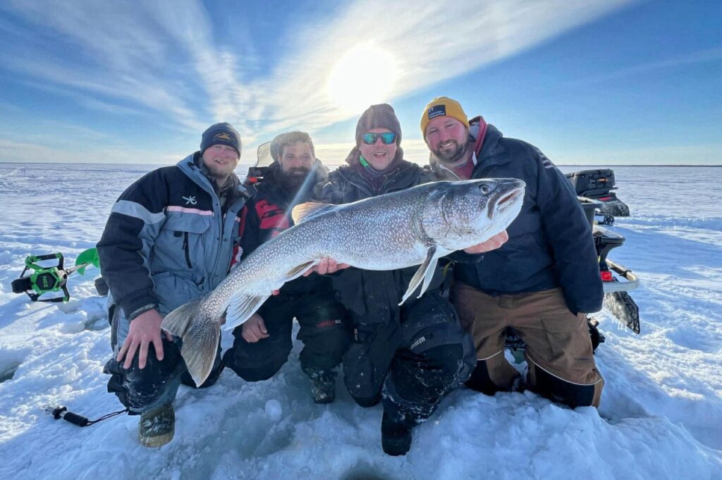 group of friends ice fishing for trophy lake trout in Manitoba