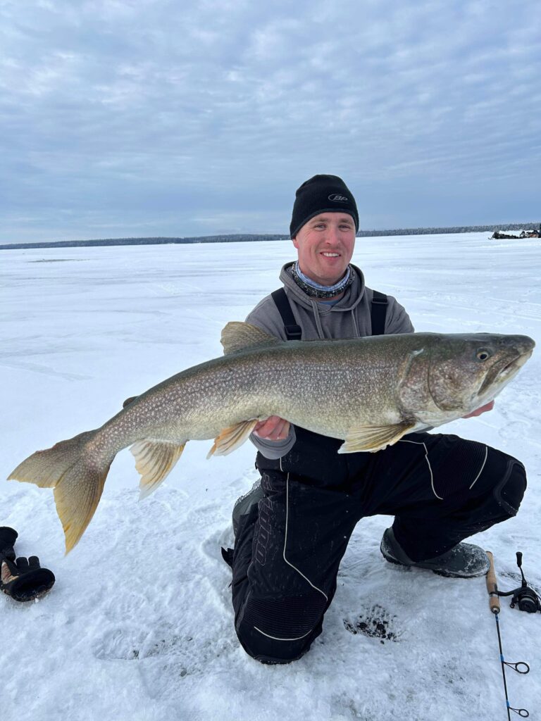 A man holding a trophy fish at while Ice Fishing at Lake Athapapuskow