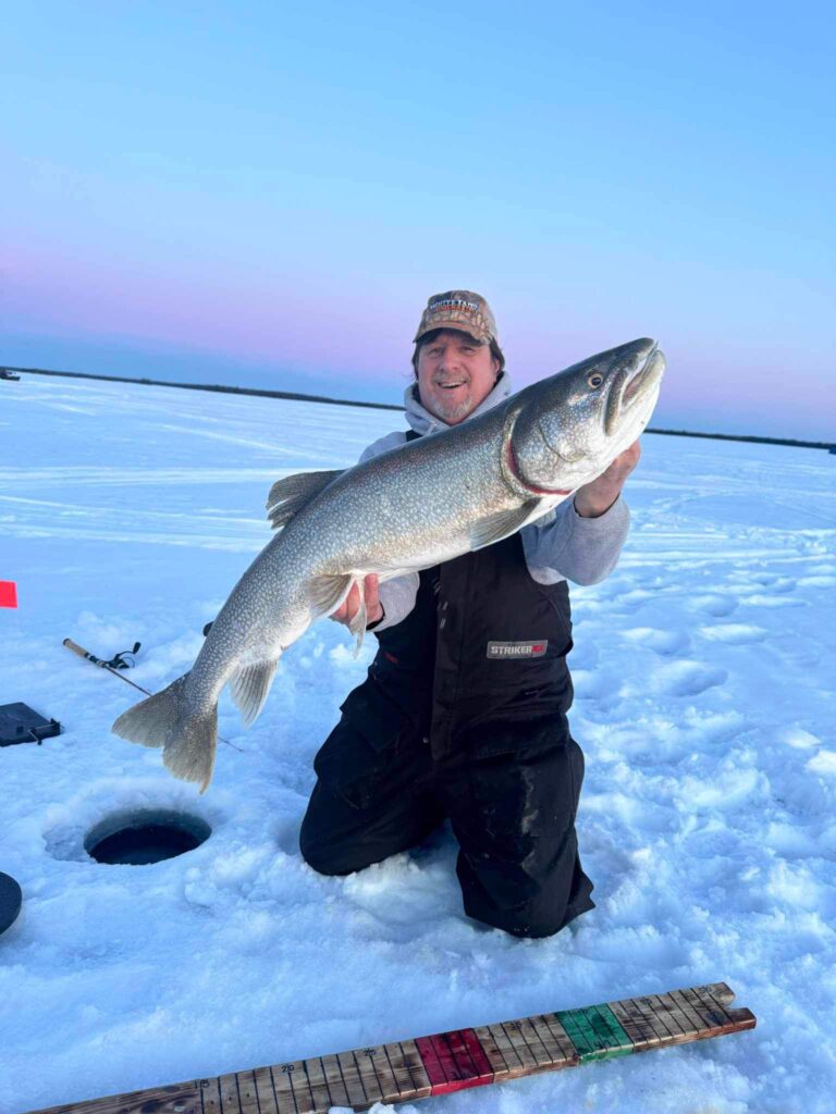 A man holding his trophy catch on an ice fishing adventure in Manitoba