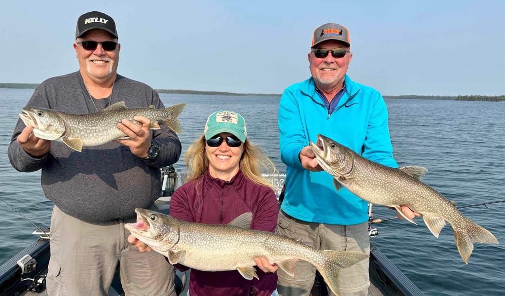 A group of friends on a boat showing off their catch at one of the best fishing lodges in Manitoba.