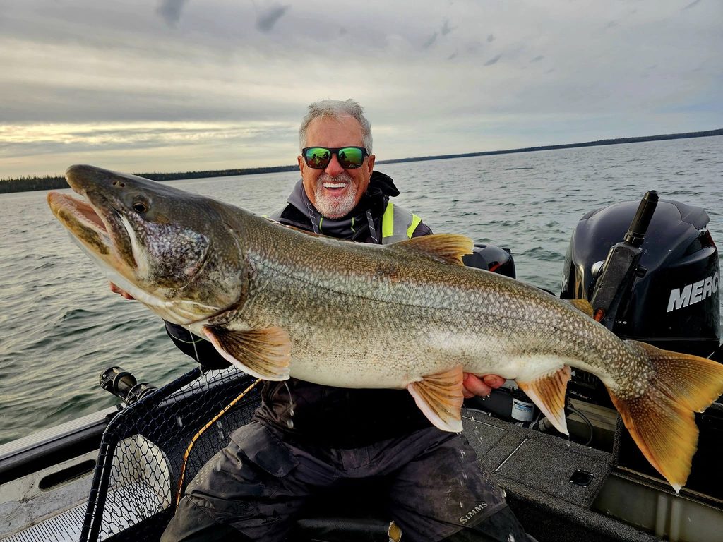 Angler holding a trophy lake trout during a fall fishing trip at Bakers Narrows Lodge in Manitoba