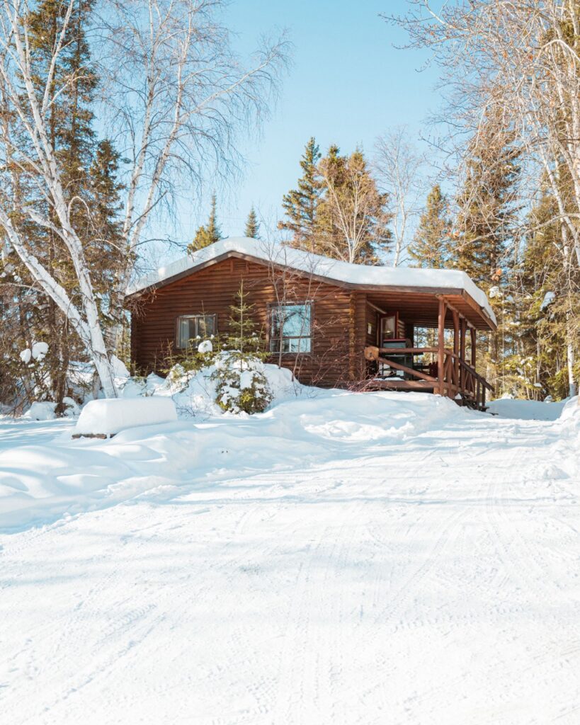 Winter scene of a cozy cabin surrounded by snow