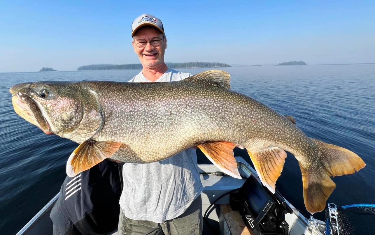 An angler on a boat holding a trophy catch at one of the best fishing lodges in Manitoba.
