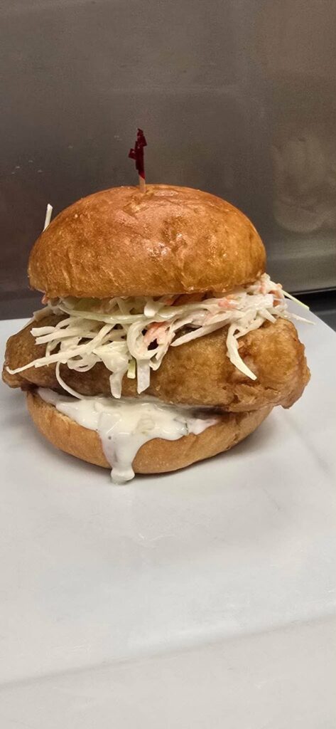Battered fish sandwich with coleslaw and tartar sauce on a toasted bun from Bakers Narrows Lodge