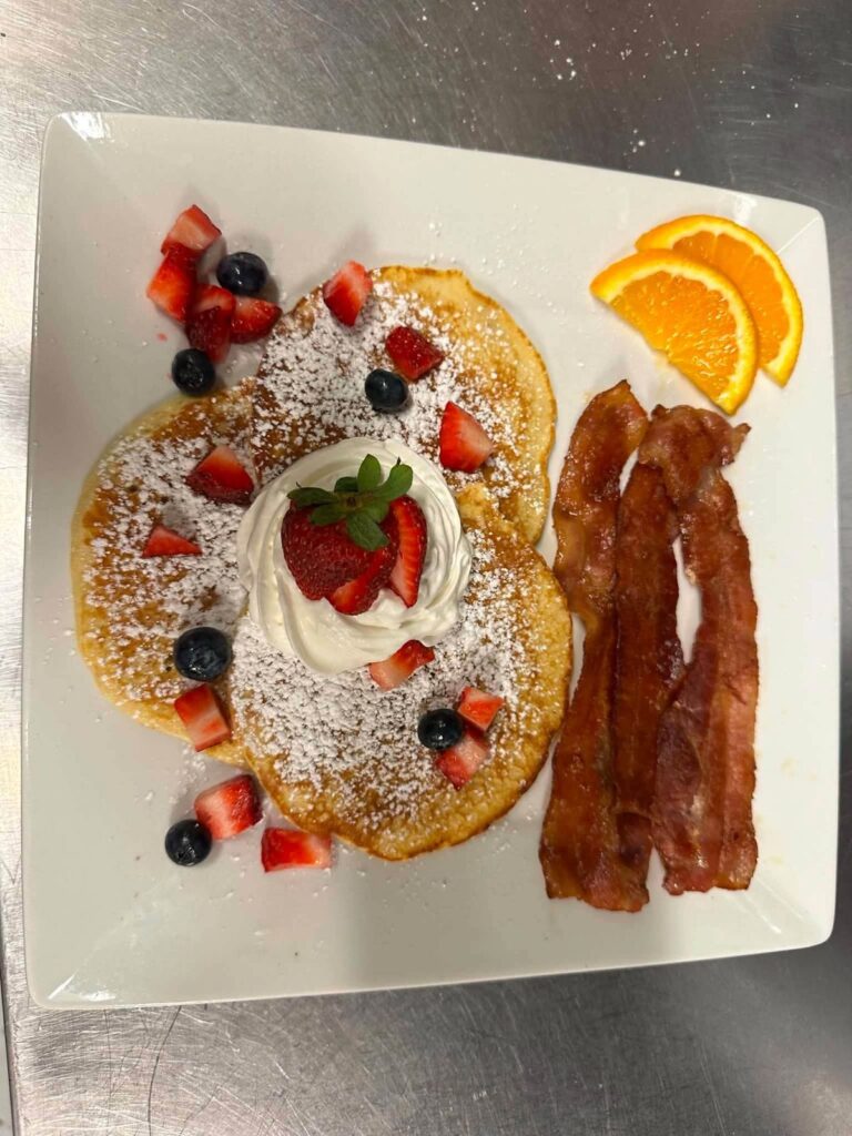 Pancakes with fresh berries, whipped cream and bacon for breakfast at Bakers Narrows Lodge