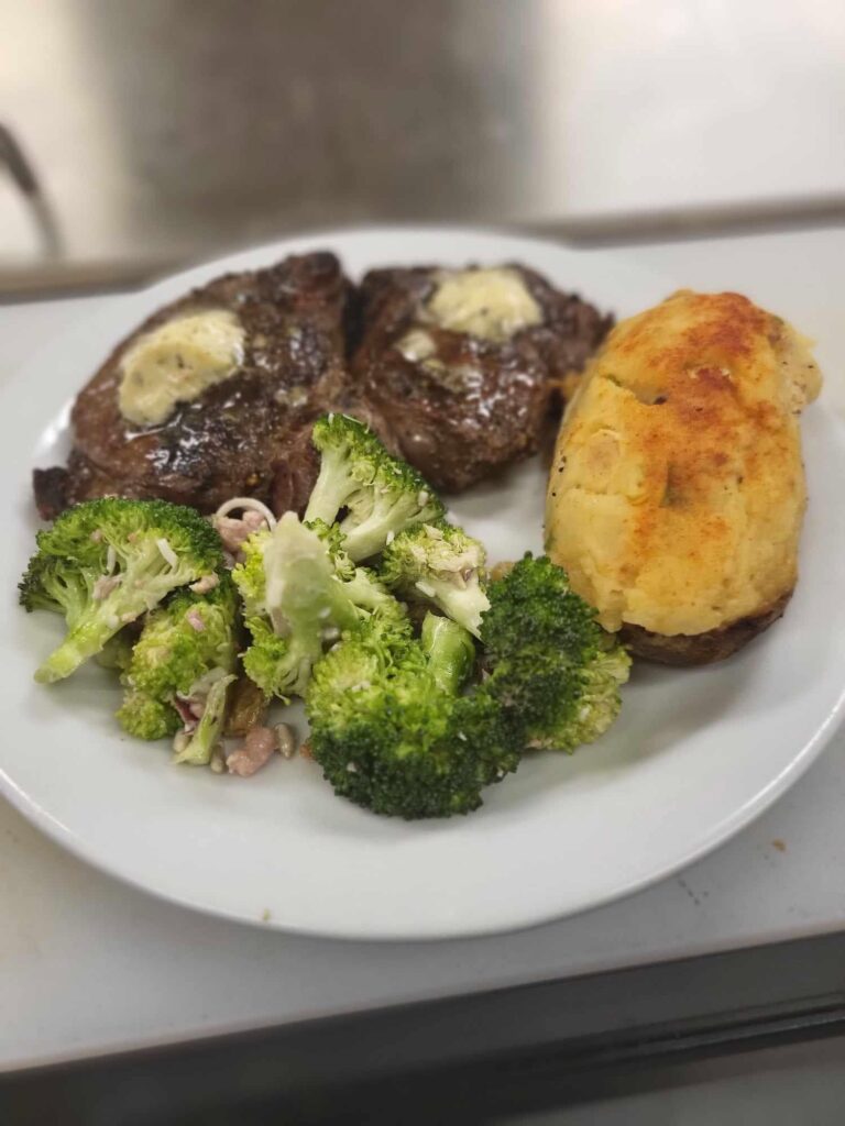 Grilled ribeye with herb butter, twice-baked potato and broccoli salad at The Club House near Flin Flon