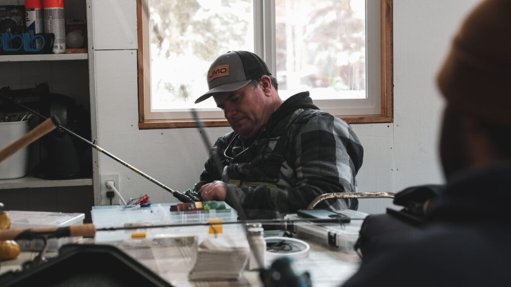 Angler rigging tackle inside the warm Kamuchawie Lake outpost lodge